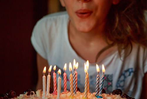 Jonge vrouw blaast kaarsjes verjaardagstaart uit